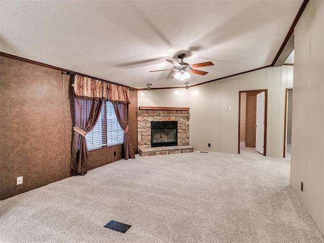 unfurnished living room featuring a textured ceiling, light colored carpet, ceiling fan, crown molding, and a stone fireplace