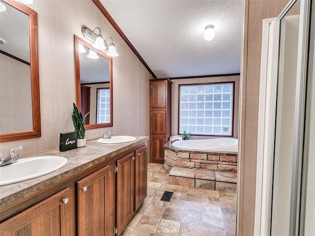 bathroom featuring tile patterned flooring, tiled bath, a textured ceiling, vanity, and ornamental molding