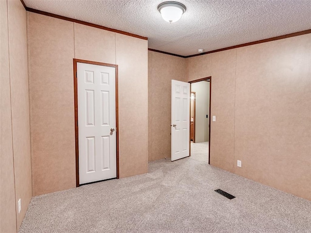 unfurnished bedroom featuring a textured ceiling, light colored carpet, and ornamental molding