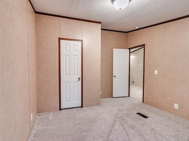 unfurnished bedroom featuring light carpet, crown molding, and a textured ceiling