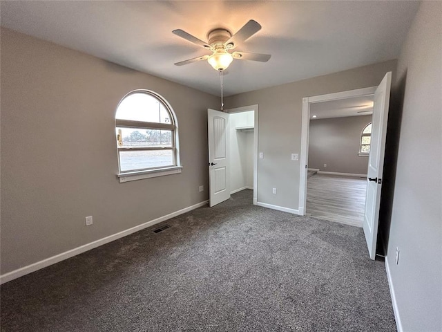 unfurnished bedroom featuring dark carpet and ceiling fan