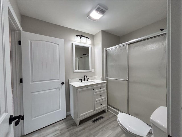 bathroom featuring toilet, vanity, wood-type flooring, and walk in shower