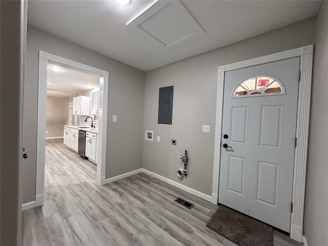 entryway with light wood-type flooring, electric panel, and sink