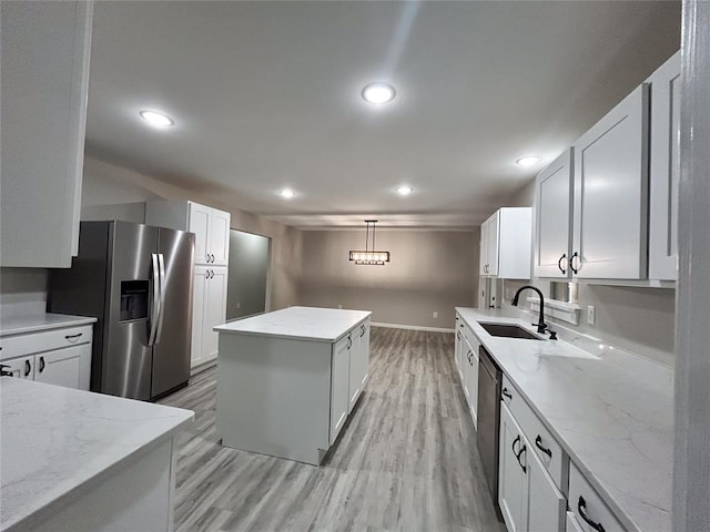 kitchen featuring sink, stainless steel appliances, light hardwood / wood-style flooring, pendant lighting, and white cabinets