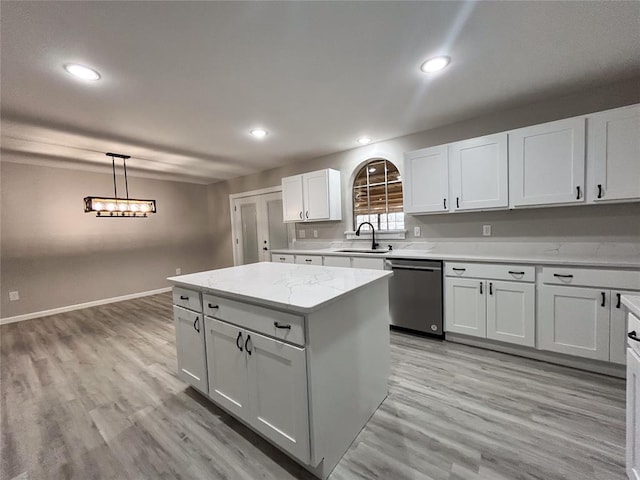 kitchen featuring sink, light hardwood / wood-style flooring, stainless steel dishwasher, decorative light fixtures, and white cabinets