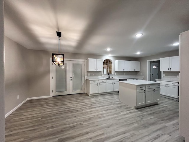 kitchen with white cabinets, a center island, light hardwood / wood-style floors, and hanging light fixtures