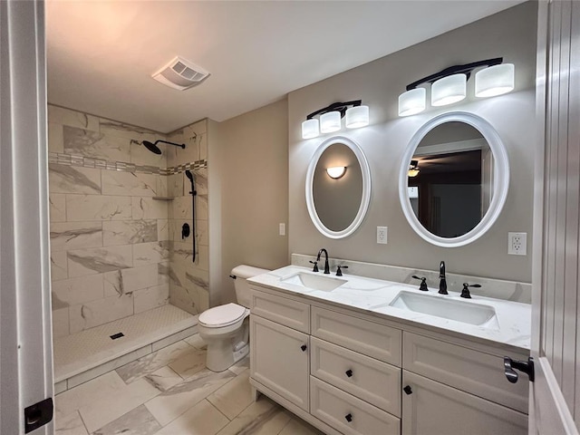 bathroom with vanity, toilet, and a tile shower