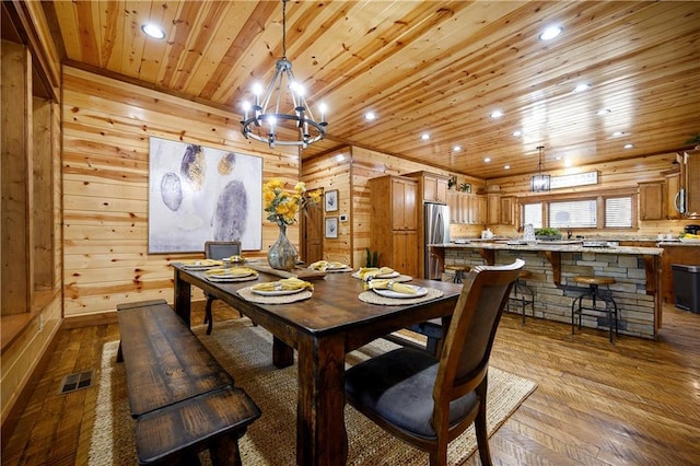 dining room with wood walls, hardwood / wood-style floors, wooden ceiling, and an inviting chandelier