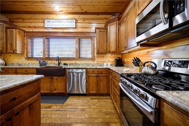 kitchen featuring wooden ceiling, sink, wooden walls, appliances with stainless steel finishes, and light stone counters