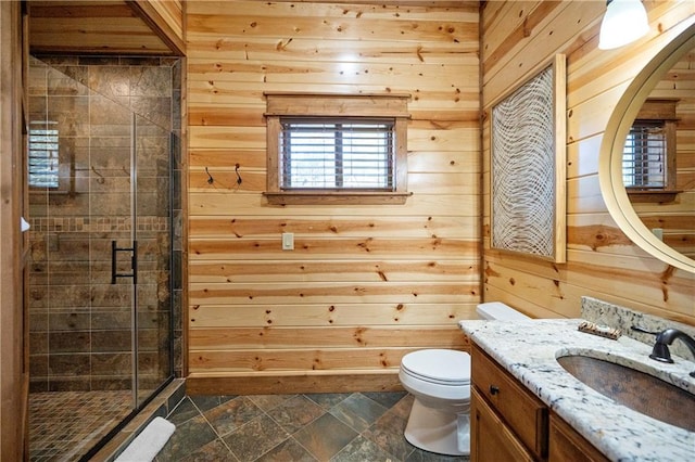 bathroom featuring vanity, toilet, a shower with shower door, and wooden walls