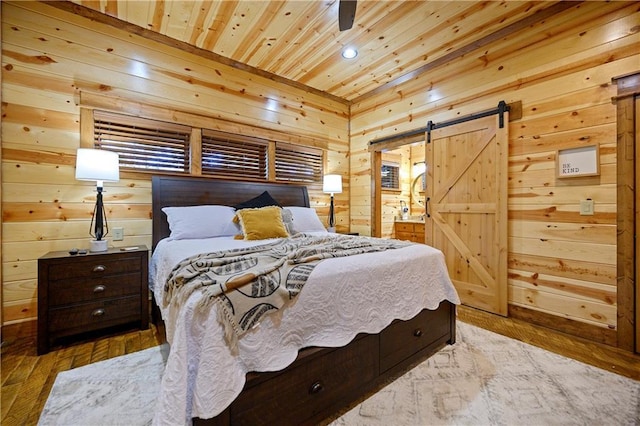 bedroom featuring a barn door, wood ceiling, wooden walls, and light hardwood / wood-style flooring