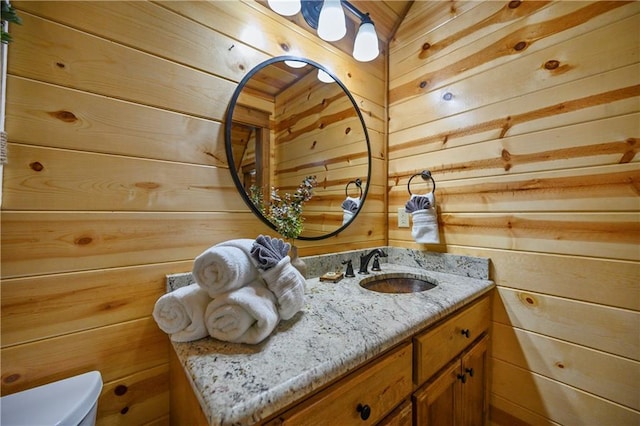 bathroom featuring wood walls, vanity, and toilet