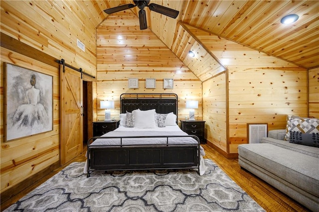 bedroom featuring hardwood / wood-style floors, wooden ceiling, wooden walls, vaulted ceiling, and a barn door