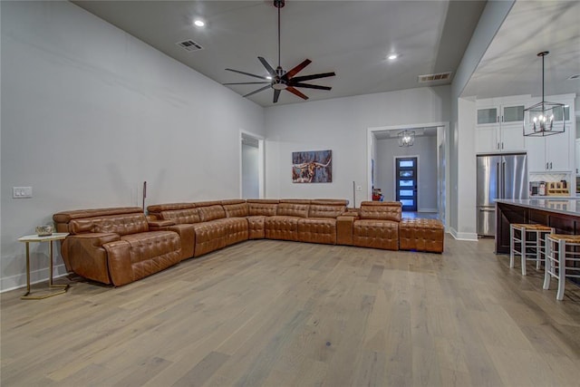 living room with light hardwood / wood-style floors and ceiling fan with notable chandelier