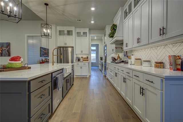 kitchen with white cabinets, decorative light fixtures, a notable chandelier, and light hardwood / wood-style flooring