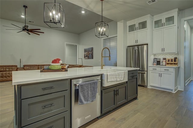 kitchen featuring gray cabinetry, stainless steel appliances, a kitchen island with sink, white cabinetry, and hanging light fixtures