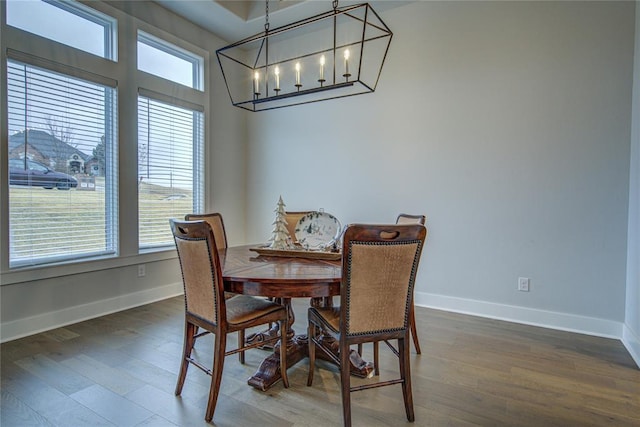 dining room with dark wood-type flooring and an inviting chandelier