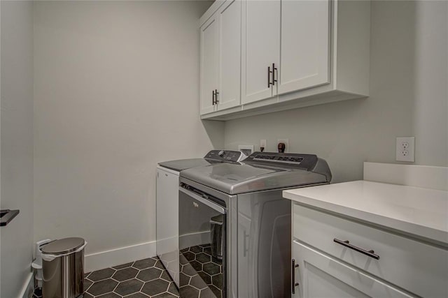 laundry room featuring cabinets, dark tile patterned floors, and washing machine and clothes dryer