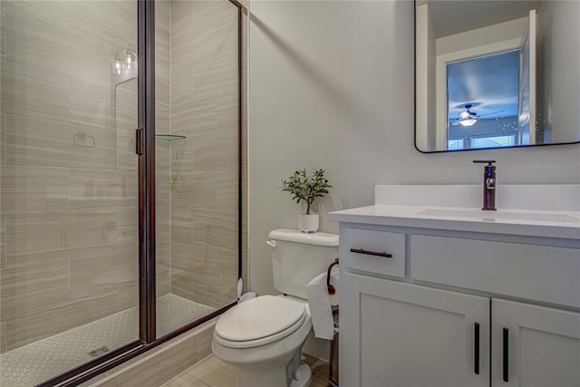 bathroom featuring vanity, ceiling fan, toilet, and a shower with shower door