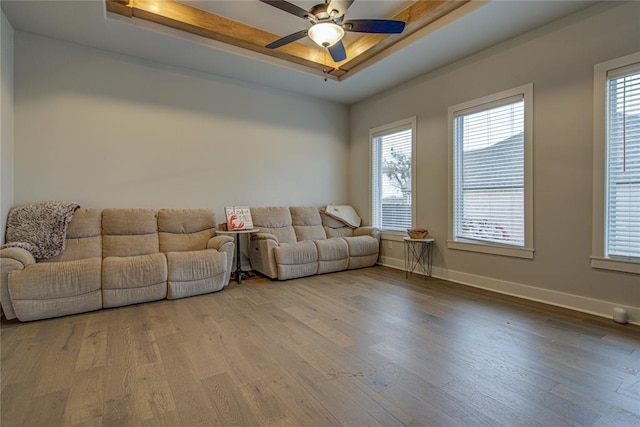 living room with hardwood / wood-style floors, ceiling fan, and a tray ceiling