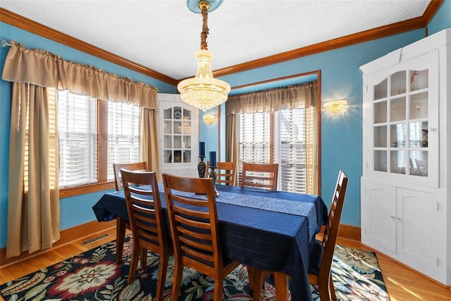 dining room with crown molding, a chandelier, a textured ceiling, and light hardwood / wood-style floors