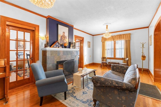 living room featuring crown molding, light hardwood / wood-style floors, a textured ceiling, and an inviting chandelier