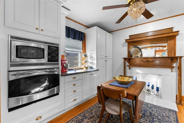 kitchen with white cabinetry, ceiling fan, stainless steel appliances, light hardwood / wood-style flooring, and ornamental molding