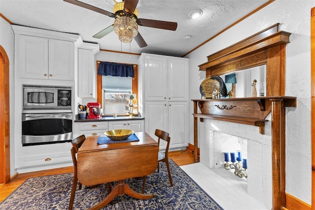 dining area with crown molding, ceiling fan, a textured ceiling, and light wood-type flooring