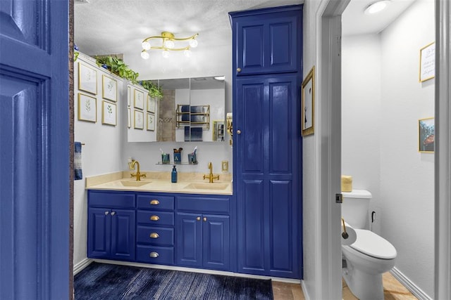 bathroom featuring vanity, a textured ceiling, and toilet