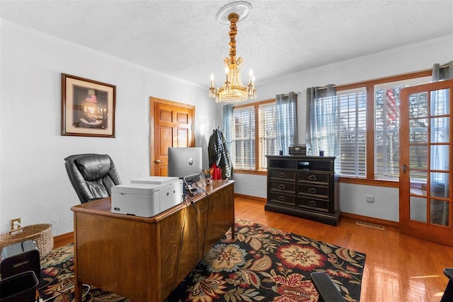 office area featuring light hardwood / wood-style flooring, ornamental molding, a textured ceiling, and an inviting chandelier