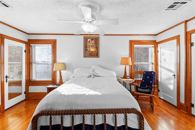 bedroom with a textured ceiling, light hardwood / wood-style floors, ceiling fan, and ornamental molding