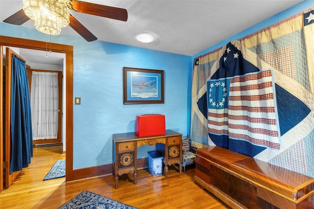 office space with ceiling fan with notable chandelier, hardwood / wood-style floors, and a textured ceiling