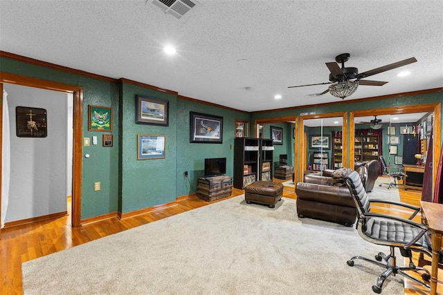 home office featuring ceiling fan, wood-type flooring, a textured ceiling, and ornamental molding