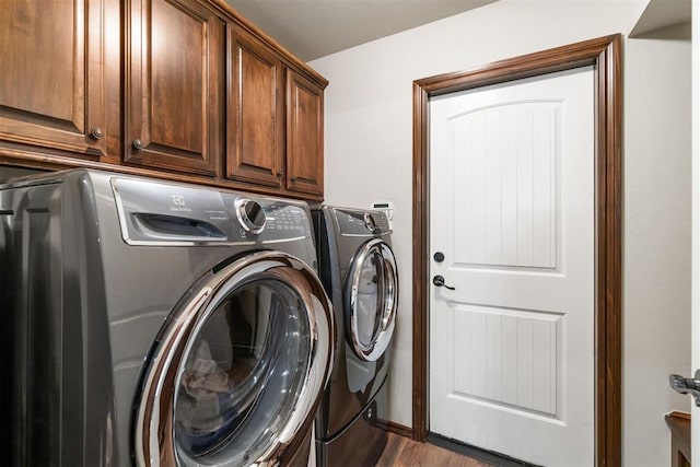 laundry area with cabinets, washer and dryer, and dark hardwood / wood-style floors