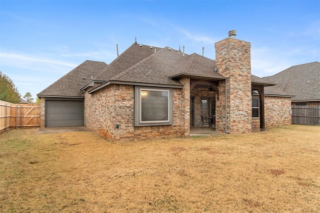 back of house with a garage and a lawn