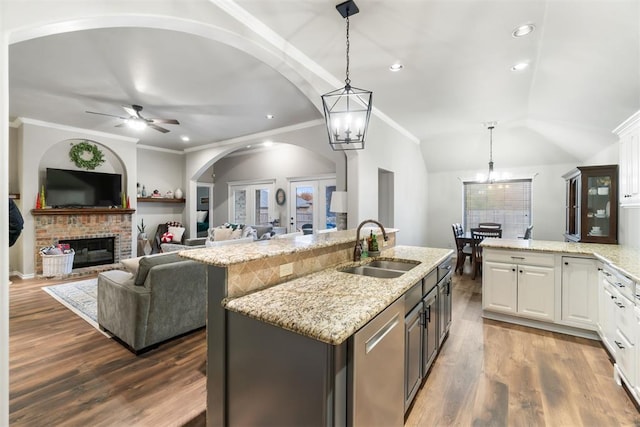 kitchen featuring white cabinetry, sink, hanging light fixtures, a brick fireplace, and dark hardwood / wood-style floors