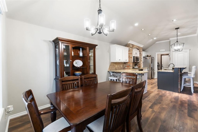 dining space with sink, an inviting chandelier, dark hardwood / wood-style floors, lofted ceiling, and ornamental molding