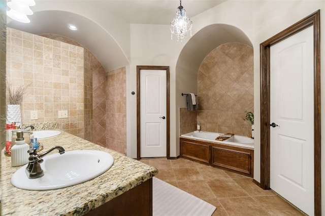 bathroom featuring a washtub, vanity, tile walls, and tile patterned flooring