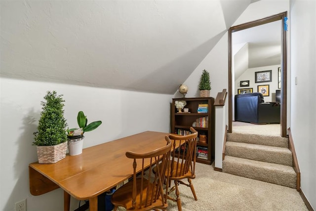 carpeted dining space featuring vaulted ceiling