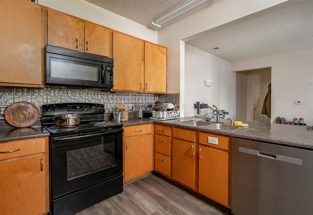 kitchen with sink, tasteful backsplash, dark hardwood / wood-style flooring, a textured ceiling, and black appliances