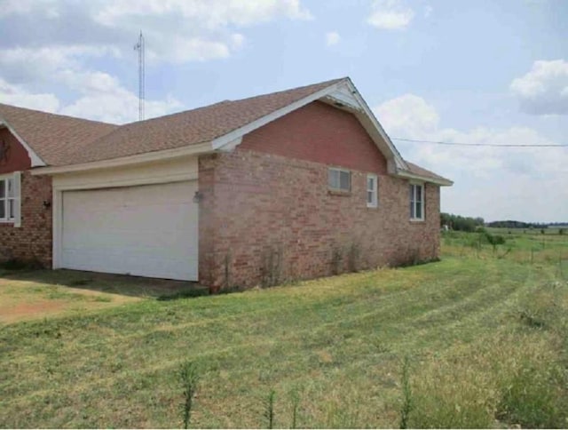 view of side of property featuring a garage and a yard