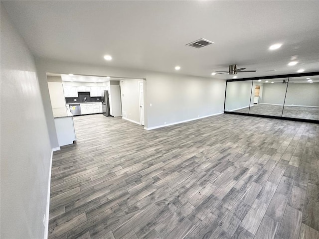 unfurnished living room with wood-type flooring and ceiling fan