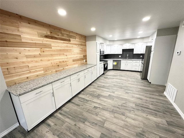 kitchen with sink, light hardwood / wood-style floors, light stone counters, white cabinetry, and stainless steel appliances