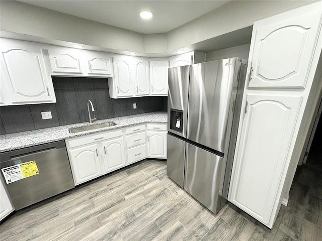 kitchen with white cabinets, light wood-type flooring, stainless steel appliances, and sink