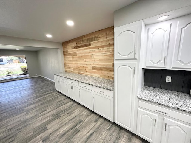 kitchen with white cabinets, wood-type flooring, and light stone countertops