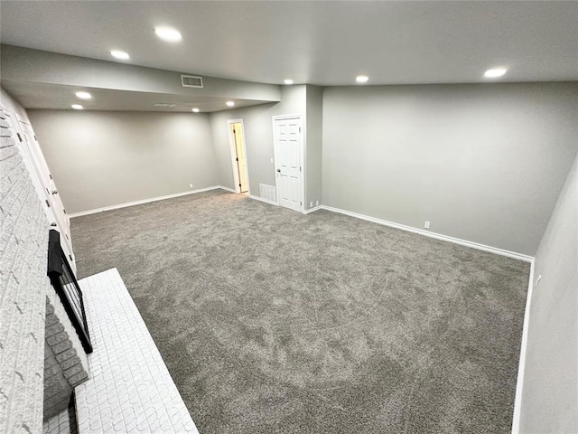 basement featuring a fireplace and dark colored carpet