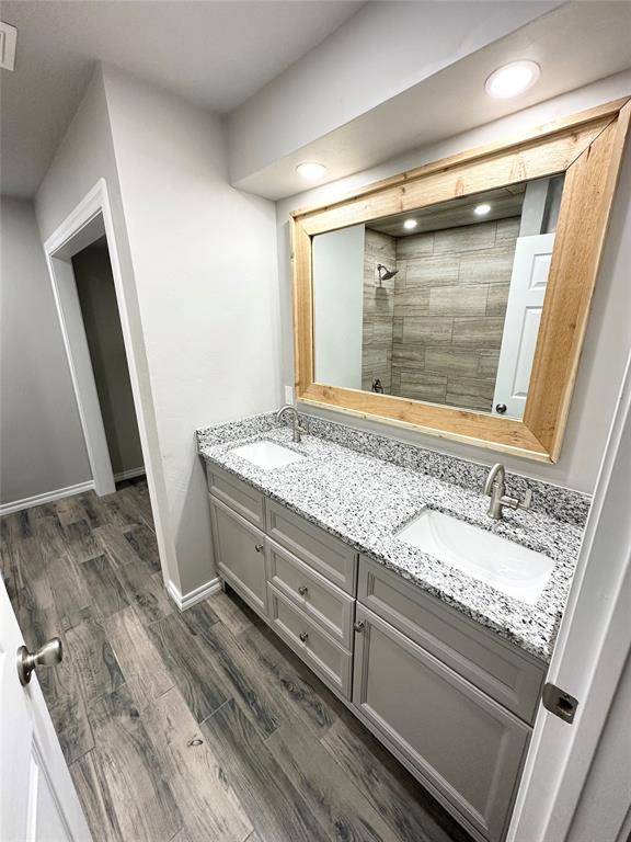 bathroom with tiled shower, vanity, and hardwood / wood-style flooring