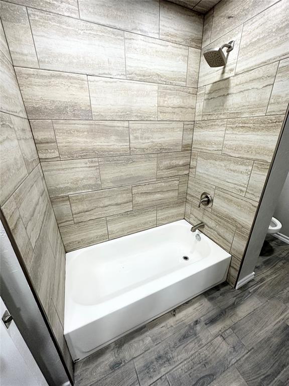 bathroom featuring tiled shower / bath combo and toilet