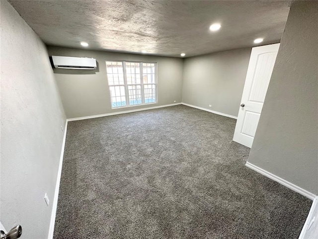 carpeted spare room featuring an AC wall unit and a textured ceiling