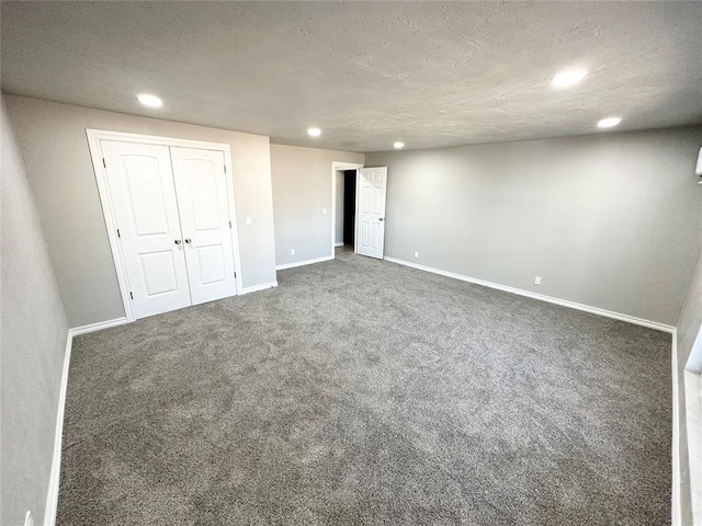 unfurnished bedroom featuring a closet, a textured ceiling, and dark colored carpet